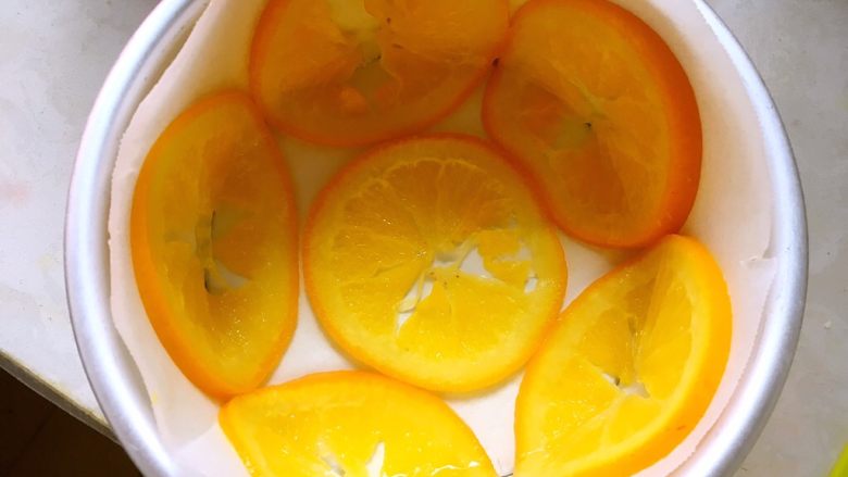 橙香蛋糕（6寸）,为了方便脱模，模具底下铺油纸，侧面也围一圈油纸，将橙片滤干汤汁，如图铺在模具底部及边缘