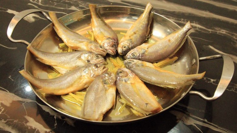干锅黄花鱼,将腌制好的黄花鱼摆入锅中