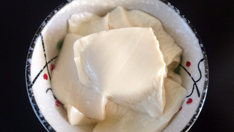 自制豆腐脑,绢豆腐用勺子舀薄片到碗中