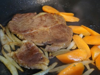 牛排,加入胡萝卜。
肉两面都煎过，这时候来一个淋油，作法是在煎肉的过程中把平底锅稍微提起来一点，让油跟肉汁集中在一个角落 ，在用汤勺舀起油纸淋回肉表。
做法很简单，但是烹饪出来的成品效果更好，损失的水分比较少，
牛排煎到自己喜欢的程度关火即可出锅。