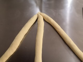 奶香辫子面包,取三根长条将它们的一端重叠在一起压紧。
