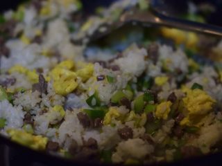 牛肉蛋炒饭,米饭炒散后，倒入鸡蛋牛肉蔬菜，加糖，烹入料酒。