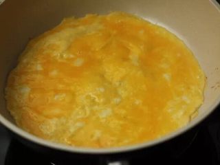蘑菇培根蛋卷,4. 平底锅热油，加入一半蛋液平摊成蛋饼。半熟就关小火。