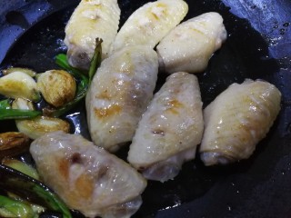 梅子（话梅）鸡翅,炒菜的铁锅烧热后倒入煎好的鸡翅，油也放一点进去，同时把刚才挑出来的葱姜蒜瓣也放进锅里