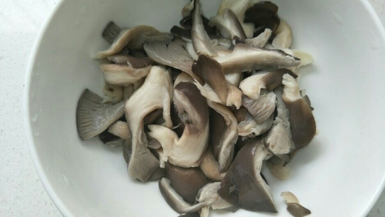 炸蘑菇,把焯好水的蘑菇，过一下凉水，挤干净水放入一个大碗中。