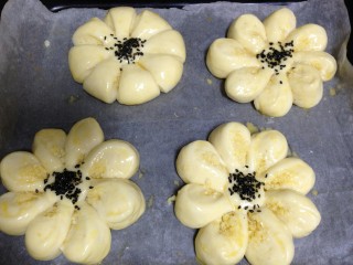 花朵在餐桌绽放―花朵椰蓉包,发酵好的椰蓉包表面刷蛋液，中间撒少许黑芝麻做装饰，烤箱180度预热
