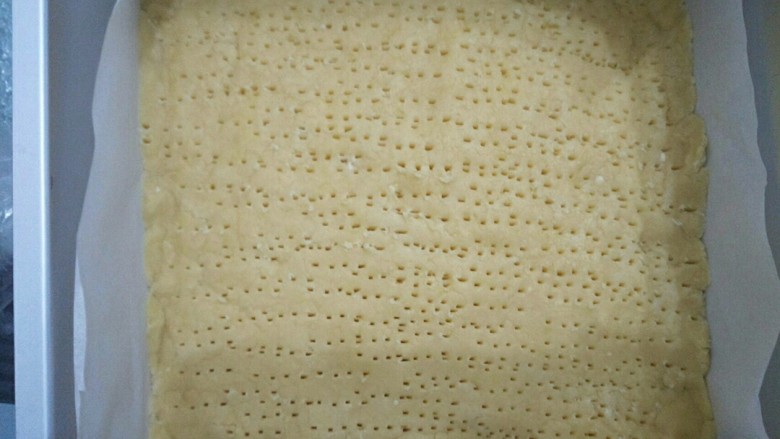焦糖核桃酥饼,擀成与八寸方型模具大小的面皮，放入垫有油纸的模具中，并用叉子叉出小孔。垫油纸便于脱模，压小孔避免烤的过程面皮鼓起。