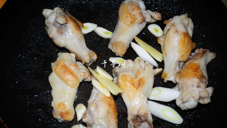 可乐鸡翅根 带给你不一样的吃鸡感受,两面都煎好之后，将葱姜蒜、八角和桂皮放入锅中煸炒出香味来。

