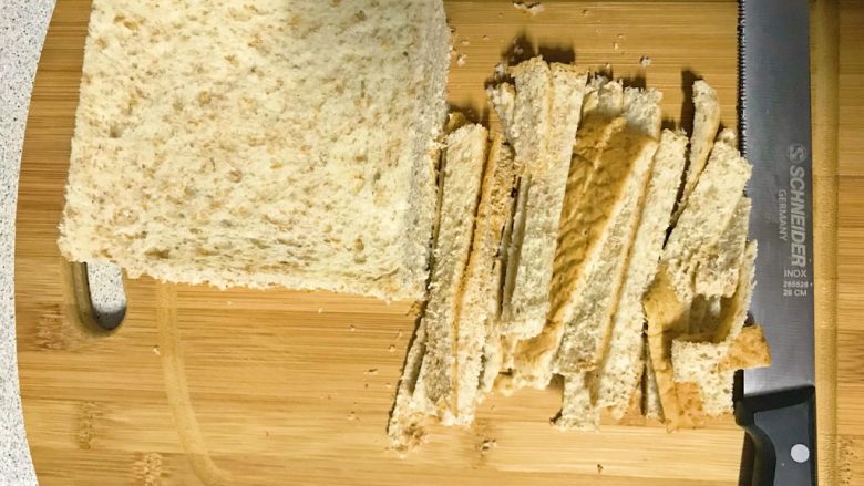 烤香肠吐司卷,用面包刀切掉边缘。