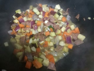 培根炒米,加入胡萝卜丁、杏鲍菇、茄子、青椒丁快速翻炒。