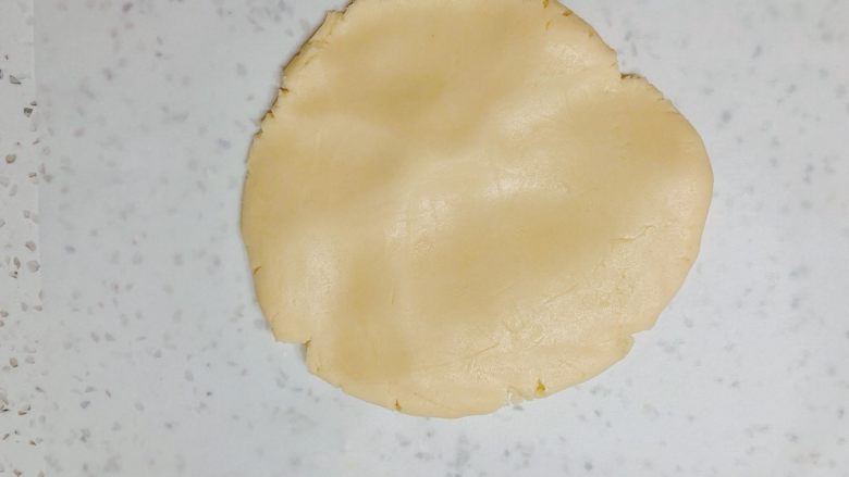 超平整口感佳的糖霜饼干底,台面垫一张油纸，把饼干面团放在上面，先用手掌按平一些。