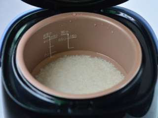 土豆腊肠焖饭,大米淘洗干净后，放入电饭煲内，按煮饭键开始煮饭
