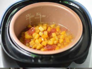 土豆腊肠焖饭,接着打开电饭煲，将土豆和腊肠铺在米饭上，盖上盖子，继续煮饭程序