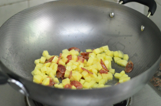 土豆腊肠焖饭,锅里烧热油，依次放入腊肠、土豆拌炒