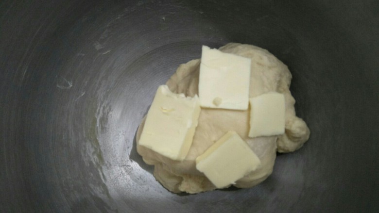 蔓越莓花环面包,面团揉到不粘手时加入软化的黄油继续揉面。