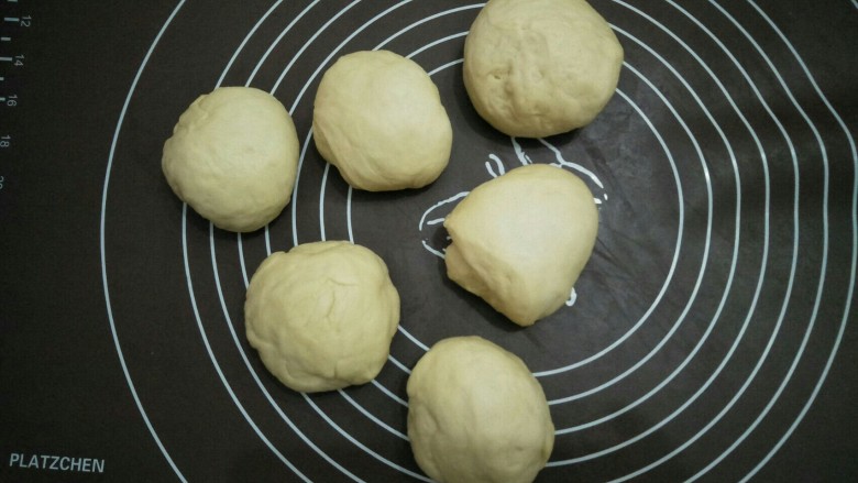 蔓越莓花环面包,将发酵好的面团放在案板上揉一会排气后分成六份。盖布醒发五分钟。
