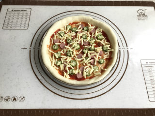 秋葵肉肠披萨,铺一层薄一点的秋葵和火腿肠，并撒一层少量的马苏里拉奶酪。