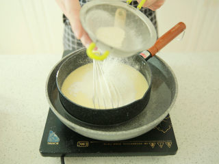 蓝莓乳酪派,锅里加放清水，小火加热，把装有芝士糊的锅放在清水里面，筛入低筋面粉，用手动打蛋器搅拌均匀
