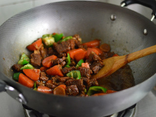 胡萝卜烧牛腩,最后放入青椒，调入盐和白糖，并大火翻炒收汁至浓稠即可