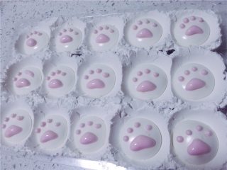萌猫爪棉花糖,将剩余的1/3蛋清中用牙签取用一点色素，搅拌均匀，调和出粉红色。然后也装入裱花袋中，剪开一个比画猫爪还要小的口子，一点一点画出其中的肉垫。