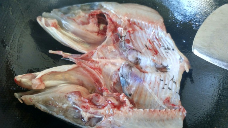 萝卜炖鱼头,将鱼头放入锅内，鱼背朝下，用油煎。