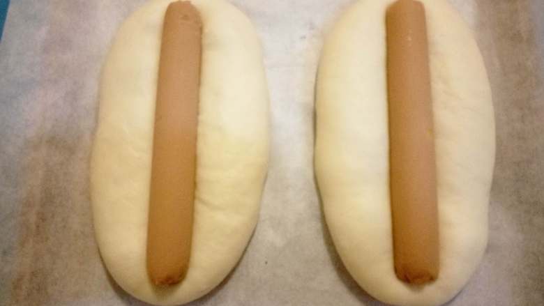 火腿肠香葱面包 ,二次发酵完成后，将火腿肠放入面包中间，轻轻往下按 