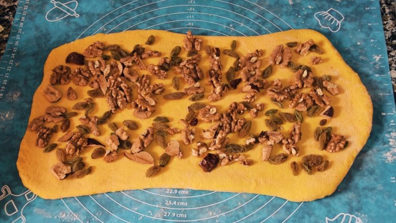 栗味南瓜黄金坚果吐司,面团擀成长方形，宽度要是吐司模具的长度。开始撒上准备好的配料。