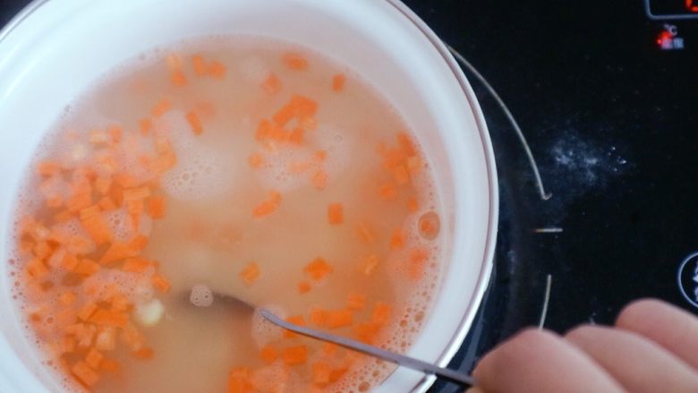 宝宝辅食之玉米胡萝卜粥,倒入后需用勺子经常搅拌以免糊锅，这里我们可以用中小火慢慢熬