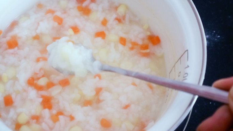 宝宝辅食之玉米胡萝卜粥,粥变得粘稠了，水份也明显减少了，米粒也都打开了这样就差不多好了，在熬几分钟就可以了