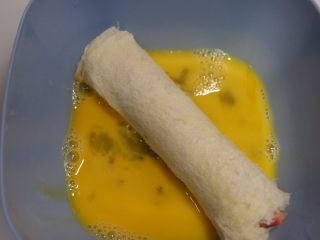 快手早餐—香肠吐司卷,将吐司卷放在蛋液里，均匀的裹粘上鸡蛋液
