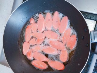 一个人的午餐_西红柿鸡蛋拌面,接着煎火腿肠，用筷子把它们铺平，底下那面微微变色后就翻面，待到两面都变色，就装盘。