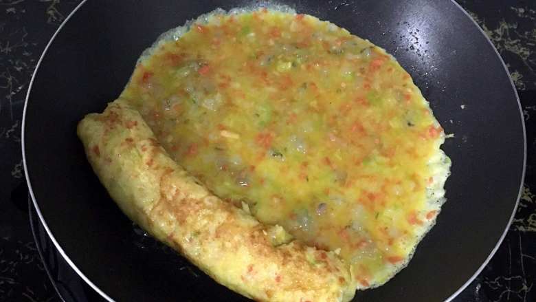 宝宝辅食之虾仁蔬菜厚蛋烧,11.待底部凝固后马上卷起。放到锅的一边。将剩余的蛋液倒入锅里。