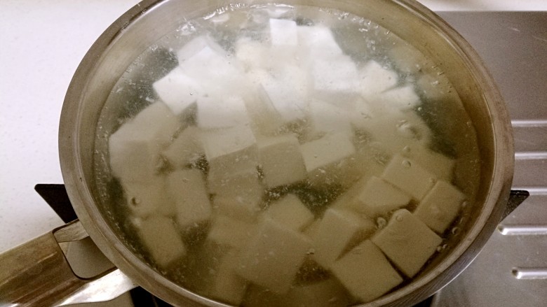 红烧豆腐,锅中烧水，水开后放入豆腐，煮一会儿后捞出。