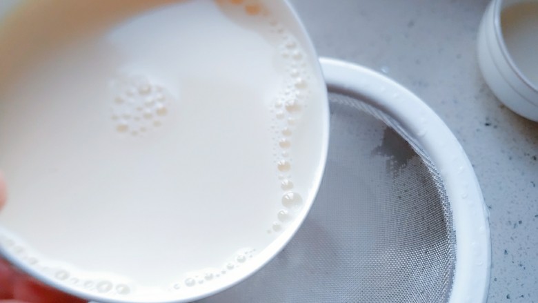 简易双皮奶,将搅拌好的牛奶通过滤网倒到有斜嘴的量杯或者有斜口的壶里。