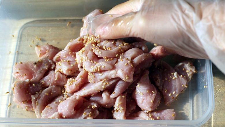 秘制牙签肉,将猪肉细片沥干水份，倒入10克生白芝麻抓匀。