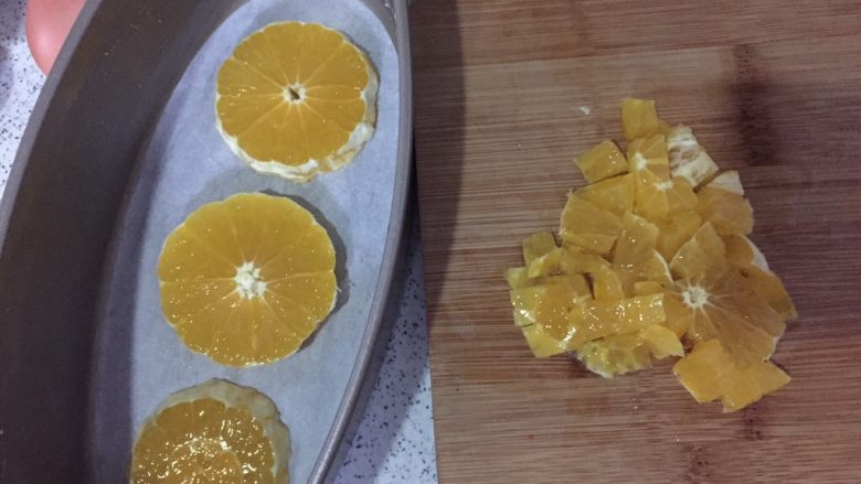橙香磅蛋糕,轻乳酪蛋糕盒，抹一层薄薄的<a style='color:red;display:inline-block;' href='/shicai/ 887'>黄油</a>，垫上油纸，一个橙子剥皮切片，摆蛋糕模底部，剩下的切丁
预热烤箱170度10分钟