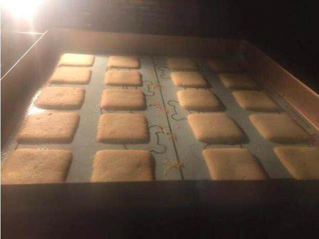 北海道白色恋人饼干,第五步，轻轻地将模具揭开，烤箱预热175度，高低火带风模式烘烤10-13分钟，观察饼干如下图般边深里浅即可。
