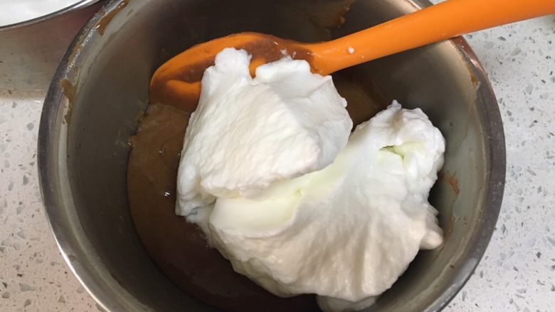 可可戚风蛋糕,取1/3蛋白放入面糊中，用硅胶刮刀搅拌至均匀，注意手法是切拌，切不可画圈搅拌，容易产生面筋影响蛋糕发起效果。