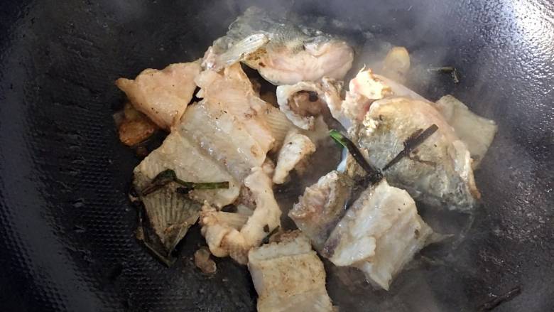 蒜苗萝卜鲈鱼汤, 鱼骨下油锅，翻炒；加入料酒，煸炒至鱼肉变色；