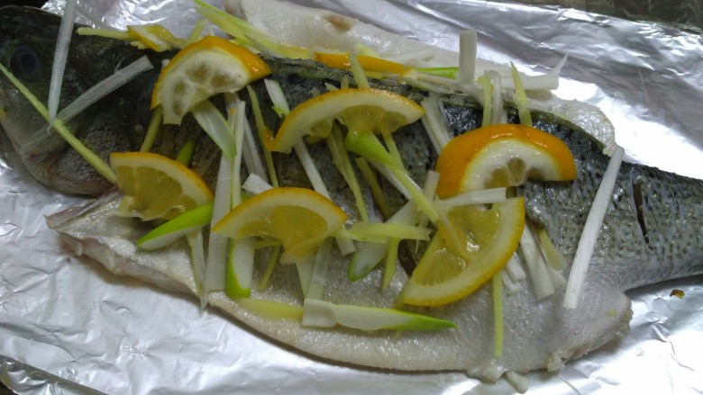 柠檬烤鲈鱼,在撒几片柠檬，烤箱预热，入烤箱180度烤20分钟