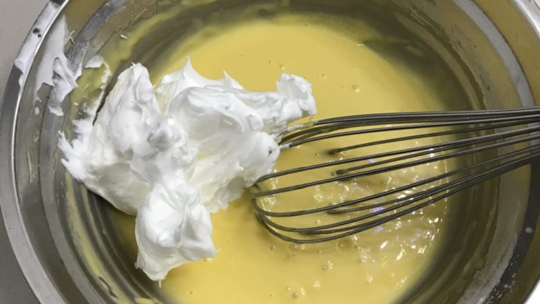 蜂蜜戚风纸杯蛋糕,取三分之一蛋白加入蛋黄糊中，用手动打蛋器快速Z字型搅拌均匀。