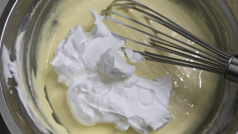 蜂蜜戚风纸杯蛋糕,加入三分之二蛋白，继续用手动打蛋器快速Z字型搅拌抣匀。