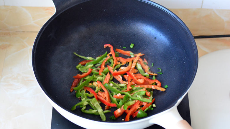 干煸鱿鱼须,锅里放少许的底油，加入切好的青红椒丝快速煸炒
