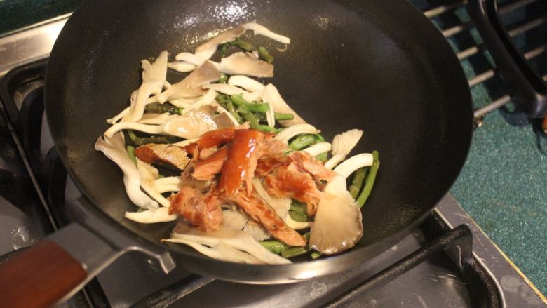 鲑鱼干凤尾菇炒春菊梗,也放入剥成小块的鲑鱼干，拌炒一下。