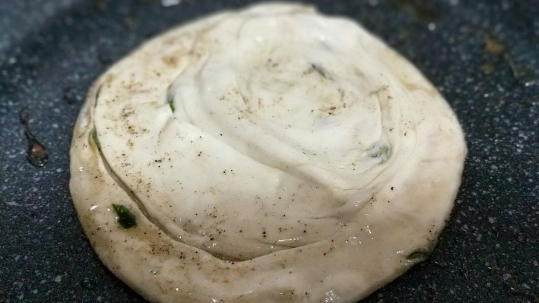 烫面椒盐葱花酥饼,不粘锅中加入食用油。将饼胚放入锅中。