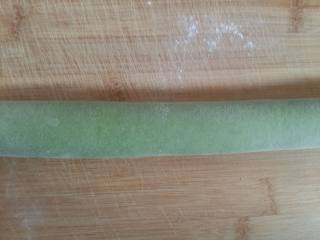 翡翠饺子,绿色面团上刷少许水，然后把白色面团放进去卷起来，搓匀。