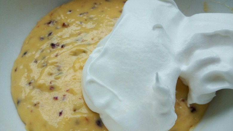 蔓越莓戚风蛋糕,盛1/3蛋白到蛋黄碗里，翻拌均匀(从底部往上翻拌，不要画圈搅拌)