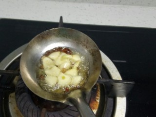 芹菜叶糊涂面,勺子里放入适量油，放入蒜瓣、花椒、茴香，小火炸香。