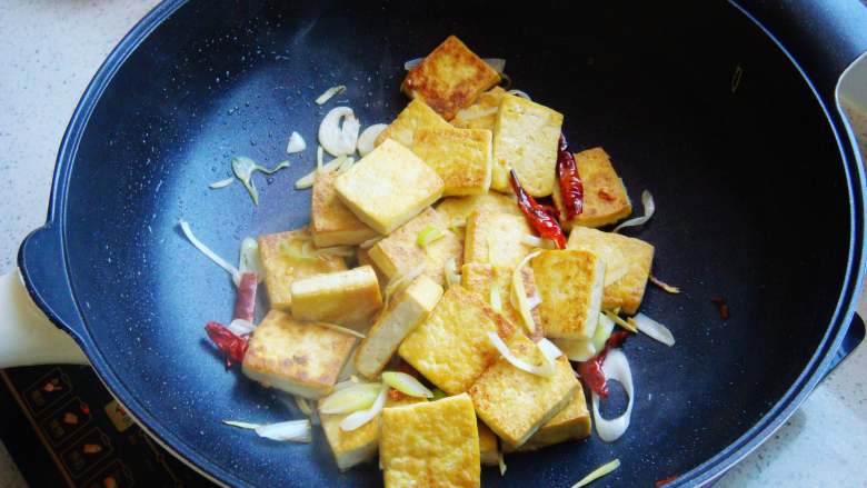 香煎家常豆腐,两面煎成金黄色，倒入葱段、辣椒、姜蒜翻炒均匀。