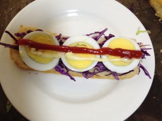 培根、芝士潜艇堡,在鸡蛋上面挤上番茄沙司和沙拉酱